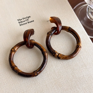 Detail of bohemian bamboo hoop earrings featuring brown tortoiseshell resin accents