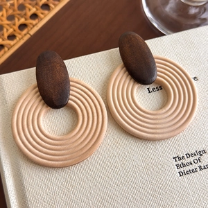 Detail of bohemian wood and resin geometric stud earrings on a textured book surface