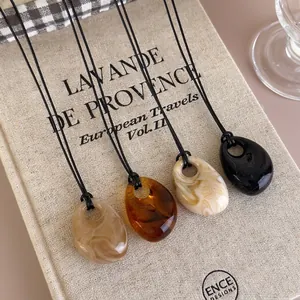Retro irregular resin pendant necklaces in amber and marble patterns on book