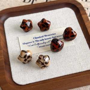Retro leopard print heart and star stud earring set on a wooden tray background