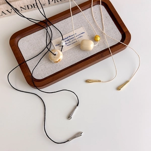 Retro ivory bead pendant necklace with marble resin ring and metallic droplets on linen