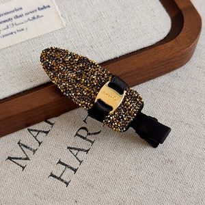 Détail de la pince à cheveux de luxe avec strass bronze et boucle dorée Smile