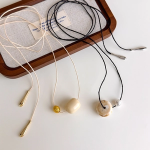 Minimalist long cord necklace with ivory round bead pendant and metallic drop accents