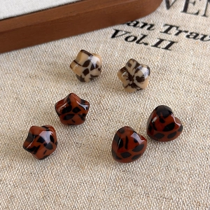 Detailed view of six-piece leopard print heart and star stud earring set on beige fabric
