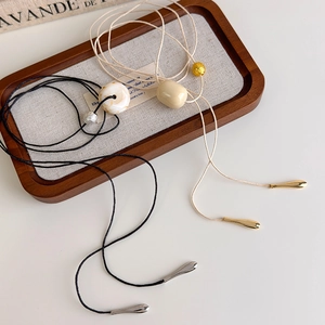 Detail of minimalist long necklaces with marble effect beads and metallic accents