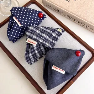 Three assorted fabric hair clips in navy polka dots, plaid, and denim with hand-made labels