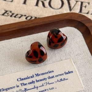 Close-up of heart-shaped leopard print earrings with high gloss resin texture