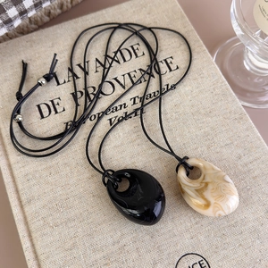 Detail of irregular marble and black stone pendants on minimalist long leather cords