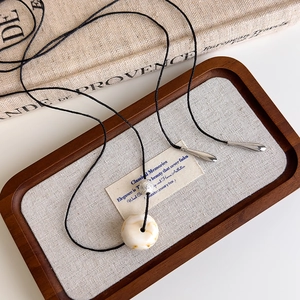 Detail of ivory marble resin pendant necklace with silver beads on a black cord