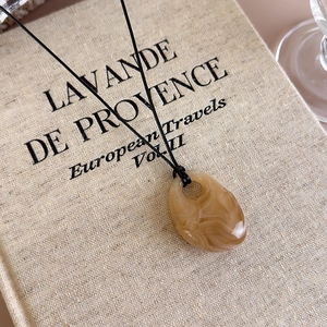 Detailed close-up of a vintage water drop resin pendant with amber marble texture
