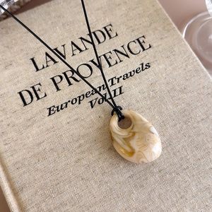 Macro shot of marble textured resin teardrop pendant on linen book background