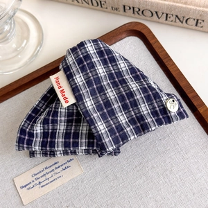 Detail of navy blue plaid fabric hair claw with handmade label and metal button decoration