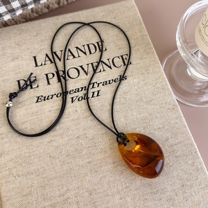 Macro shot of amber resin pendant with swirl texture on a black rope necklace