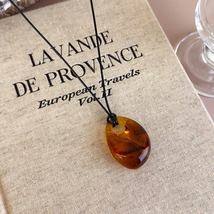 Close-up of irregular amber resin droplet pendant with black minimalist necklace cord