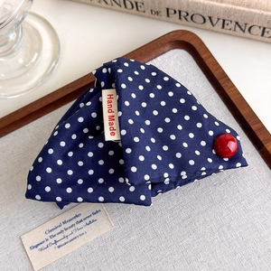 Detail of navy blue polka dot hair claw with a red button and hand made label tag