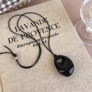 Macro detail of the dark teardrop obsidian pendant with a silver bead on a black cord