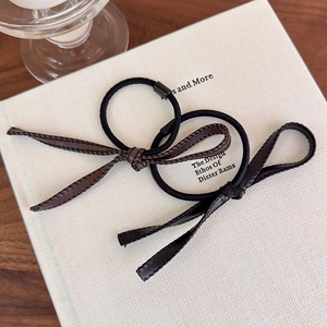 Détail d'élastiques à cheveux en cuir PU marron et noir avec coutures fines sur livre
