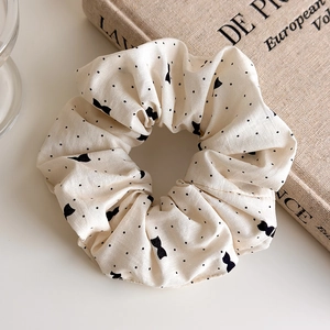 Détail d'un chouchou à pois blanc crème avec nœud posé sur un livre de style rétro