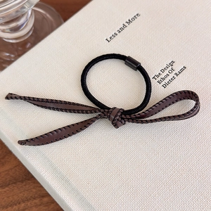 Détail macro d'un chouchou vintage en similicuir marron avec surpiqûres noires contrastées