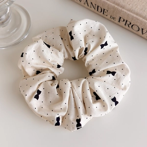 Détail d'un chouchou beige à pois et motifs de nœuds en tissu de style français