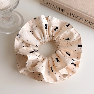Détail de chouchou beige à pois avec texture en lin et nœud élégant sur fond blanc