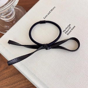 Détail d'un élastique avec nœud en simili cuir noir et finitions de couture soignées