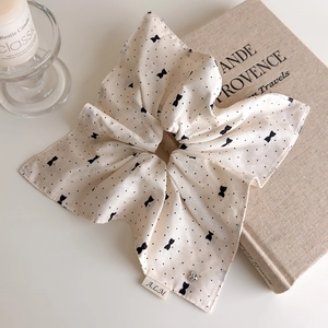 Détail du chouchou beige à pois avec étiquette A.L.M et pendentif cœur argenté