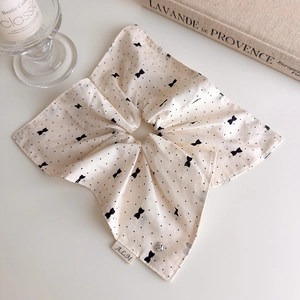 Détail d'un chouchou beige à pois avec pendentif coeur et petite étiquette de logo