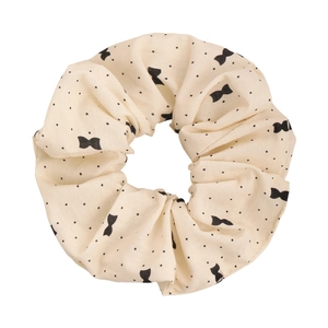 Détail d'un chouchou beige à pois avec motifs de nœuds et texture du tissu en gros plan
