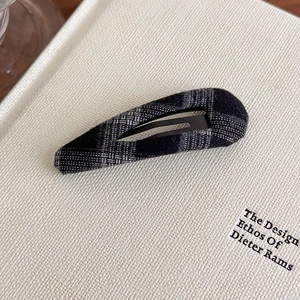 Detailed view of grey plaid fabric texture on a minimalist drop-shaped BB hair clip
