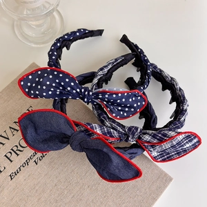 Close-up of three bow headbands in navy polka dot, denim, and plaid with red stitching