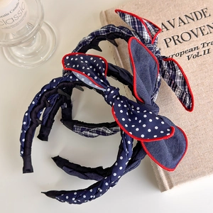 Close-up of three Korean style bow headbands with polka dots and plaid patterns on books