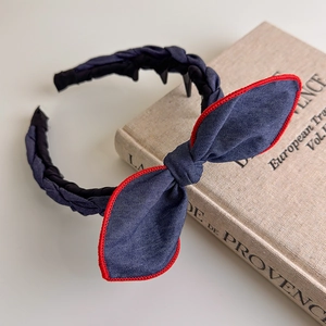 Detail of dark blue denim headband with red stitching and non-slip plastic teeth