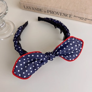 Detail of navy blue polka dot headband with red-edged bow and non-slip inner teeth