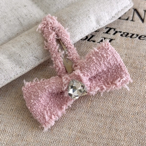 Dettaglio del fermaglio per capelli a fiocco in tweed rosa con strass a cuore