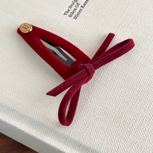 Close-up of vintage red velvet bow hair clip with gold metal smile letter buckle decoration
