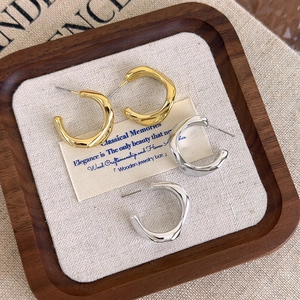 Elegant geometric gold and silver C-shaped hoop earrings with irregular liquid metal texture