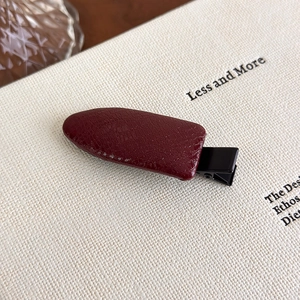 Macro detail of dark red faux leather hair clip featuring elegant crocodile texture finish