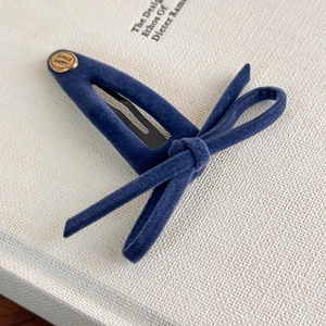 Detail of blue velvet hair clip featuring a gold medal engraved with Smile Happy text