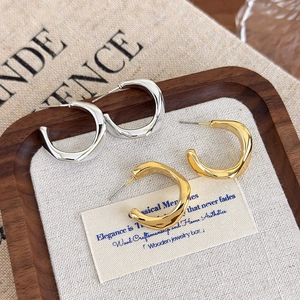 Detailed view of geometric irregular C-shaped earrings in gold and silver finish