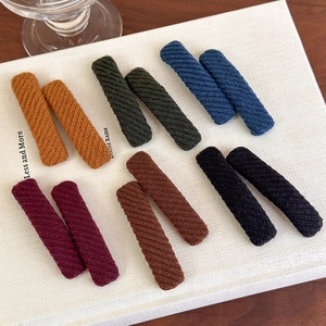 Set of 12 knit fabric covered hair clips in six vintage colors on a white book surface