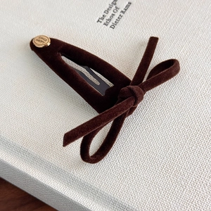 Detailed view of dark brown velvet bow hair clip with engraved smile happy gold emblem