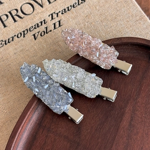 Gros plan de trois barrettes en cristal rose blanc et bleu sur un plateau chic