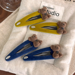 Détail de barrettes ours en velours avec pendentif Love en bleu et jaune vif