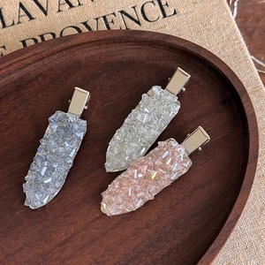 Détail de barrettes élégantes en cristal bleu, argent et rose sur un plateau en bois