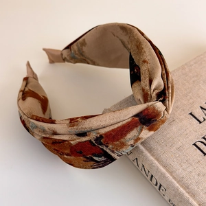Detail showing vintage tie-dye fabric headband with cross-knot on an old book background