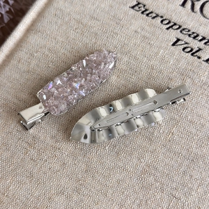 Vue macro montrant le dessus en cristal rose et le dos en métal argenté des pinces à cheveux