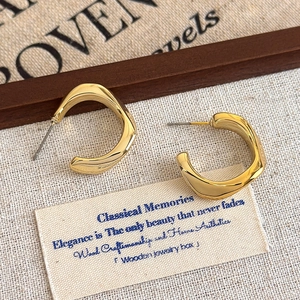 Close-up of golden irregular geometric hoop earrings with polished metallic finish