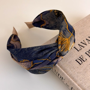 Detail view of floral tie-dye fabric headband with cross knot and textured fabric finish