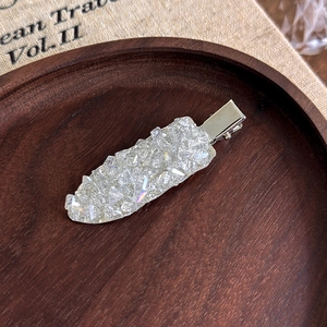 Vue détaillée d'une barrette argentée élégante avec des cristaux étincelants sur bois